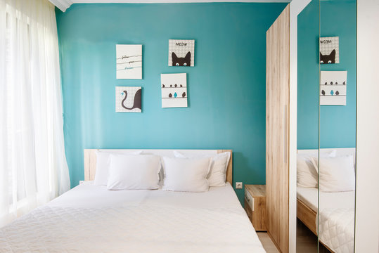 Hotel Bedroom With Blue Walls, White Curtains, Pillowcases And Sheets