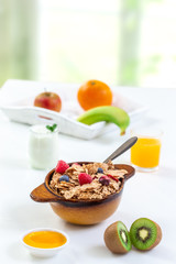Healthy breakfast with bowl of cereal, orange juice, milk, , and fruits on white background.
