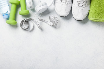 Fitness background with dumbbells, sneakers, towel, headphones and water bottle