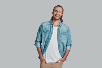 Fototapeta premium Male beauty. Handsome young man looking at camera and smiling while standing against grey background