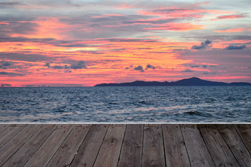 Fototapeta na wymiar beautiful pink sunset twilight orange blue sky at sea with wooden table top texture concept romantic scenic
