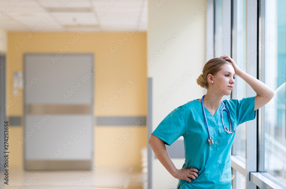 Sticker tired female nurse in hospital corridor