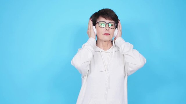 Love for music concept. Mature Woman Streams Music in Headphones on a blue background