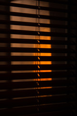 Sun filtering through venetian shades; indoor, golden sunset light.