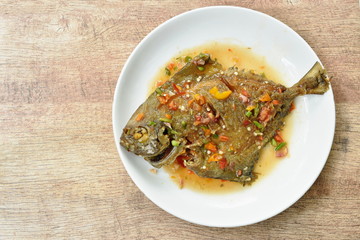 deep fried white pomfret dressing spicy sauce on plate