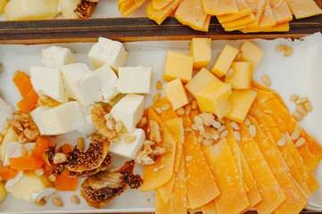 Cheese wooden plate with variety of appetizers on table
