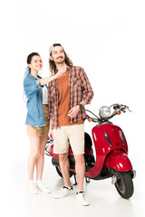 Fototapeta na wymiar beautiful girl pointing with hand and young man looking away, standing near red scooter isolated on white