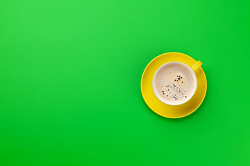 Yellow coffee cup over green background