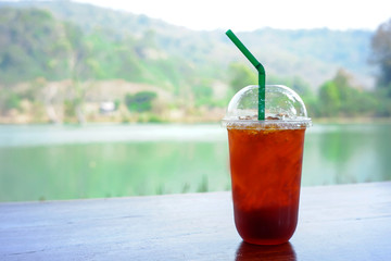 Cold lemon tea in a glass, placed on a wooden table with a natural background.