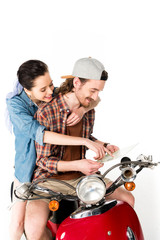 beautiful girl pointing with finger on and young man looking at map, sitting on red scooter isolated on white