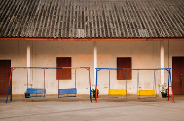 Colourful old swing in kindergarten school.