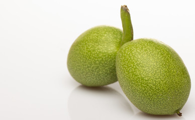 Two green walnut on a white background close-up