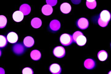 Unfocused abstract purple bokeh on black background. defocused and blurred many round light