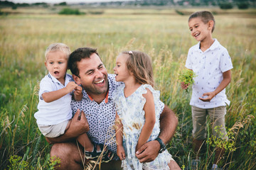 Happy dad and children having fun outdoors in a wheat field.
