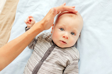 Mother stroking the child to feel the fontanel of 3 months baby boy