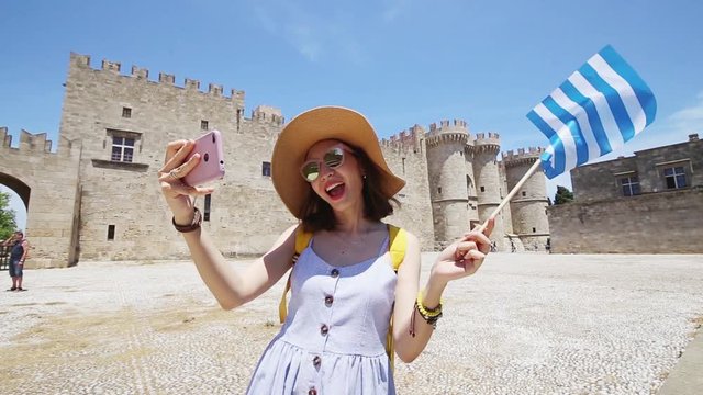 Happy asian woman with greek flag travels in Greece. Rhodes island tourist destinations