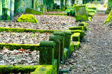 Kaputter Grabstein mit Beschädigungen auf einem Friedhof in grün