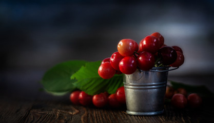 Fresh red Cherries in small metal bucket on old wooden background rural style