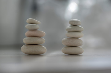 Harmony and balance, two cairns, simple poise pebbles on wooden light white gray background, simplicity rock zen sculpture