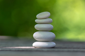 Fototapeta na wymiar Harmony and balance, cairns, simple poise pebbles on wooden table, natural green background, simplicity rock zen sculpture