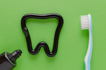 a tooth from black toothpaste, teeth care concept, toothbrush on green background