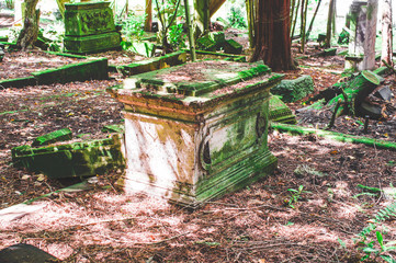 Kaputter Grabstein mit Beschädigungen auf einem Friedhof in grün
