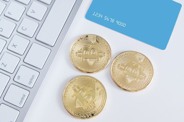 Bitcoin currency coin on a credit card. Currencies exchange concept on a white wooden desktop, top...