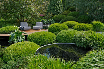 An unusual topiary arrangement of box hedges with seating and a water feature