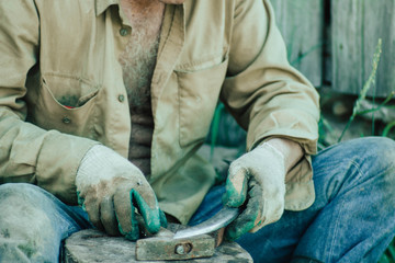 traditional iron forging, artisan sharpens a sharp knife blade with a hammer.
