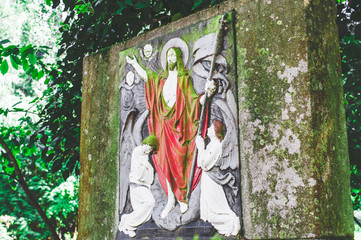 Kaputter Grabstein mit Beschädigungen auf einem Friedhof in grün