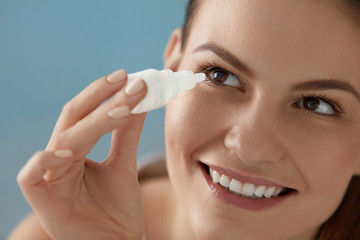 Eye drop. Woman applying lubricant eye drops in her eyes closeup