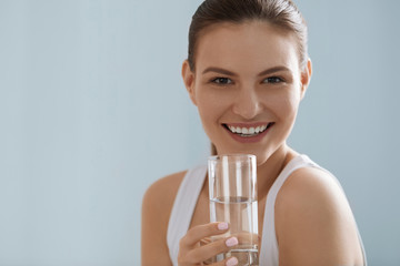 Drink water. Smiling woman holding fresh pure water in glass