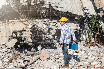 Engineer or contractor holding tool box in destruction demolishing building.
