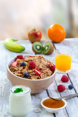 Healthy breakfast with bowl of cereal, orange juice, milk, , and fruits on white background.