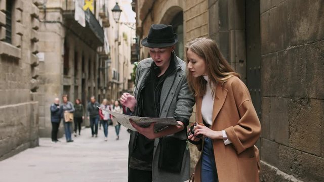 Two stylish friend standing at the street and look for something using a map