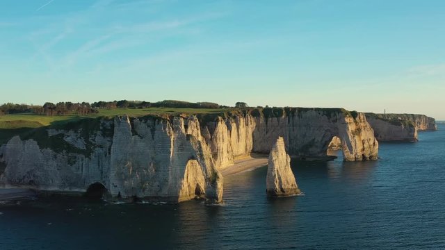 Aerial view of cliffs of Etretat at sunset (during golden hour), picturesque scenery with white cliffs and Atlantic Ocean - Normandy, France, panorama of Europe from above