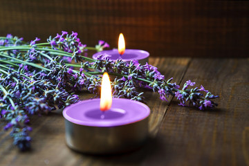 Spa massage setting with lavender flowers, scented aroma candles on wooden background. Close-up....
