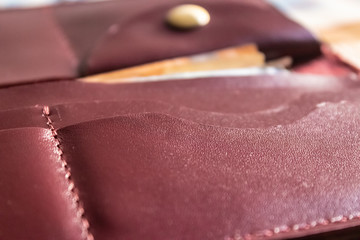 Maroon leather wallet pockets closeup  - Image