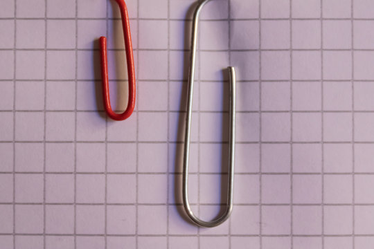 Red plastic and metal paper clips on the notebook page closeup - Image