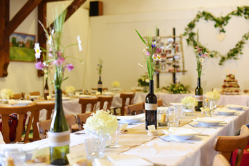 Wedding. Banquet. The chairs and round table for guests, served with cutlery, flowers and crockery and covered with a tablecloth.