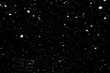 falling snow on a black background, snowfall at night, white chaotic spots on a black background