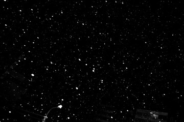 falling snow on a black background, snowfall at night, white chaotic spots on a black background
