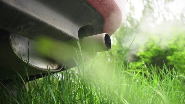 Machine pipe smoke condensate water. Closeup of machine exhaust pipe releasing fumes in the air. Green grass