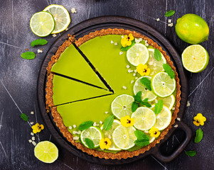 Cheesecake with slices of lime and lemon, fresh mint, candied fruit and pansy flowers