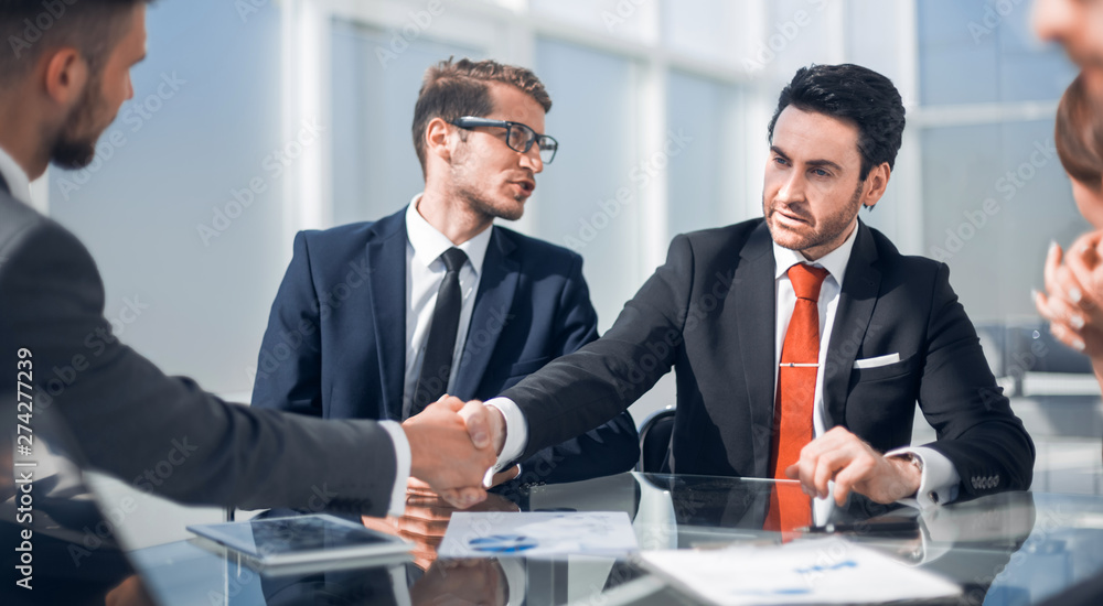 Wall mural handshake business partners at the Desk.