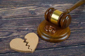 Wedding rings on the figure of a broken heart from a tree, hammer of a judge on a wooden...