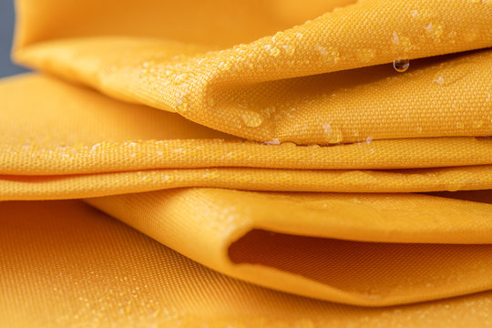 Waterproof and water repellent fabric.  Water drops on textile. Folded canvas of yellow fabric
