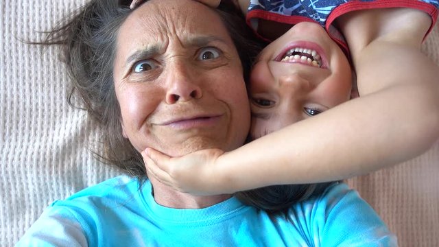 4K Comic mother and son have fun taking selfie on bed