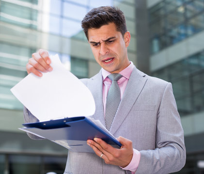 Dissatisfied businessman holding papers
