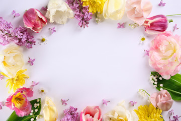 Feminine frame background made of various flowers with a lot of copy space for text. Close up, top view, flat lay.